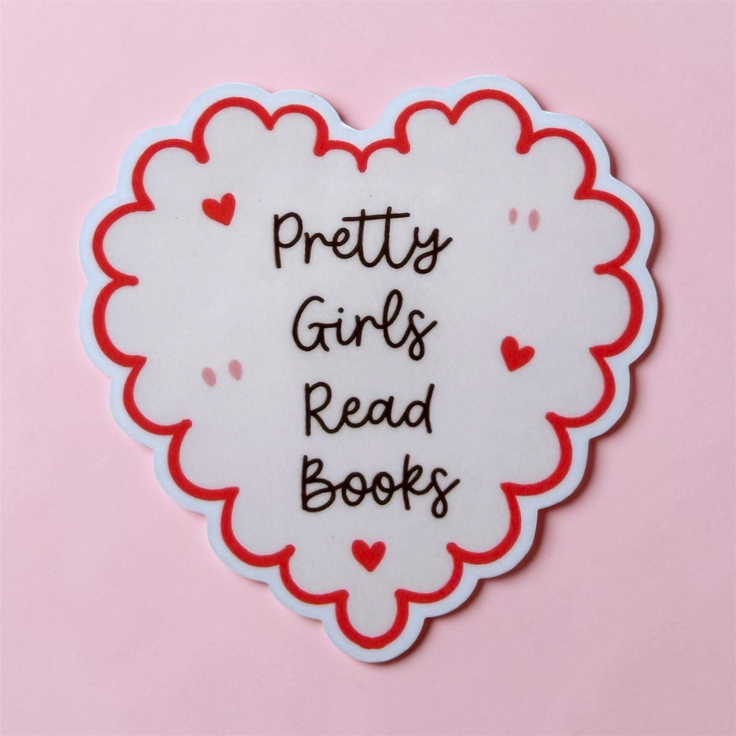 Heart-shaped sticker with 'Pretty Girls Read Books' text on a pink background