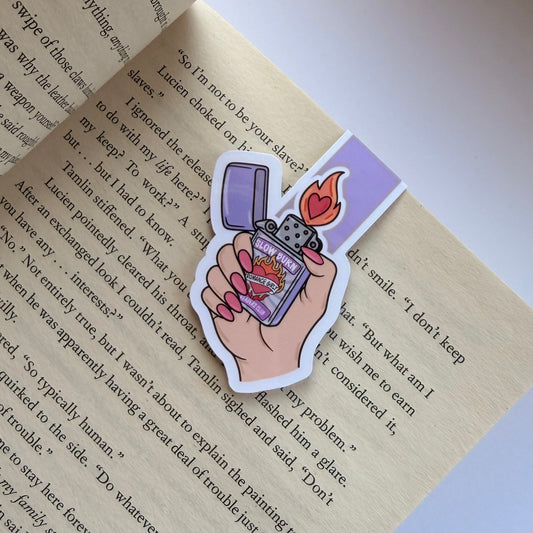 Sticker of a hand holding a lighter with flames on a book page