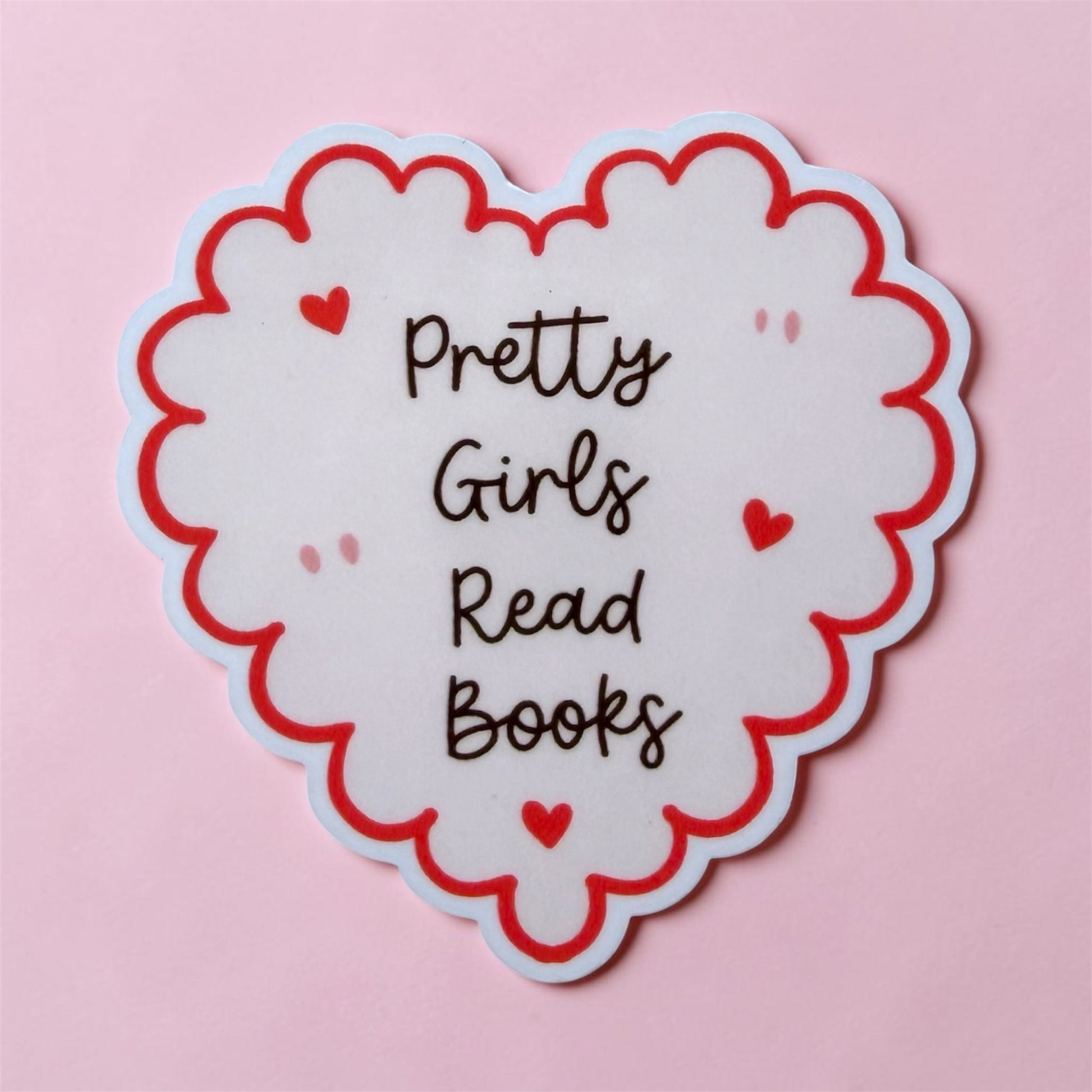 Heart-shaped sticker with 'Pretty Girls Read Books' text on a pink background